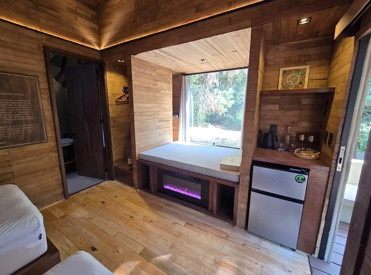 Cabin interior at Hunkápi Centre with a window seat, fireplace and forest view